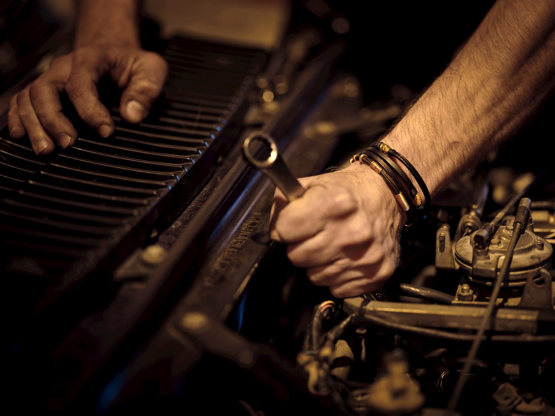 A mechanic's hands working on an engine with a wrench